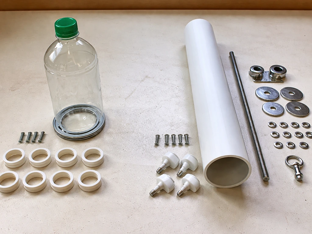Parts for two feeder builds laid out side-by-side: lazy Susan bearing and bottle vs PVC tube hardware.